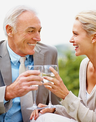 Happy couple toasting wine glasses outdoors