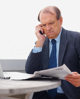 Angry senior business man reading newspaper on the phone