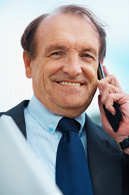 Smiling executive using cell phone over sky with clouds