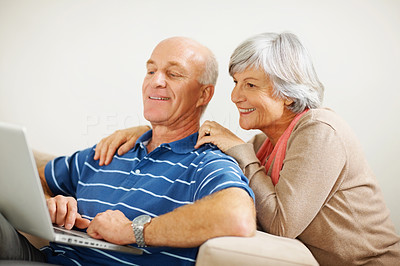 Retired woman watching husband work on a laptop