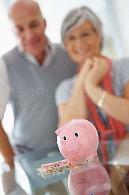 Retirement savings in piggy bank with senior couple at the back