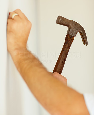 Closeup of a man hammering a nail into a wall