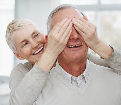 Elderly woman covering husband's eyes
