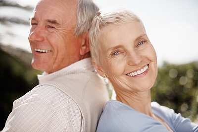 Closeup of a smiling elderly couple sitting back to back