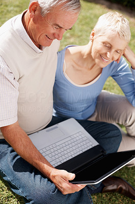 Senior couple in garden at leisure with laptop computer