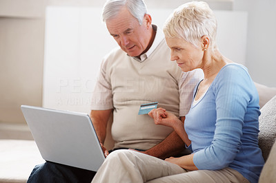 Senior couple using credit card to shop online