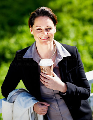 Happy business woman with a coffee cup while at the park