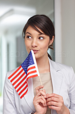 Young patriotic woman with an American flag , lost in thought