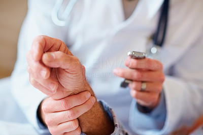 Closeup of a doctor checking the pulse rate of an old patient