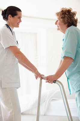 Nurse helping an old patient to stand on a Zimmer
