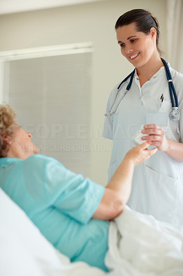 Young nurse giving a bottle of pills to a patient