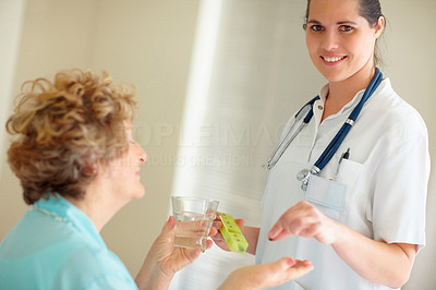 Portrait of a young nurse giving a health pill to a patient