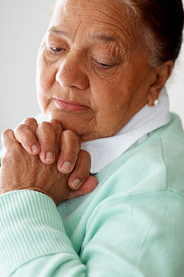 Closeup of a sad old woman with hands joined