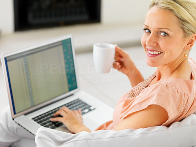 Pretty mature woman having a cup of coffee and using a laptop