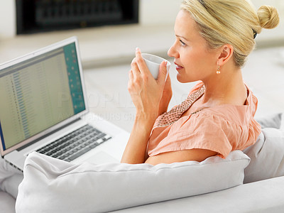 Woman drinking coffee at home day dreaming , working on a laptop