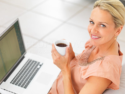 Pretty mature woman having a cup of coffee and using a laptop