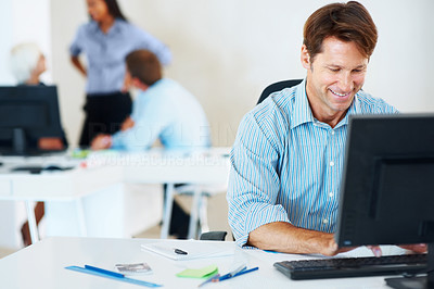 Happy businessman sitting at desk in office working on computer