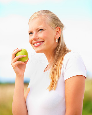 Cute young girl holding an apple smiling outside