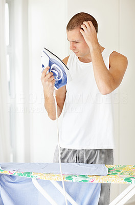 Confused middle aged man trying to iron his clothes