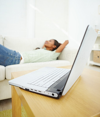 Portable laptop on the table while a female lying on a couch at