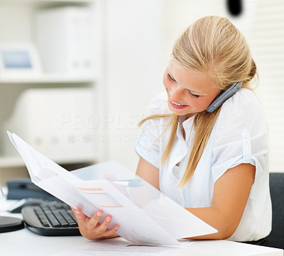 Cute business woman speaking on the phone, reading a document