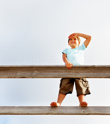 Innocent little boy standing on a railing watching out