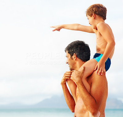 Happy man carrying his son on the shoulders while pointing away