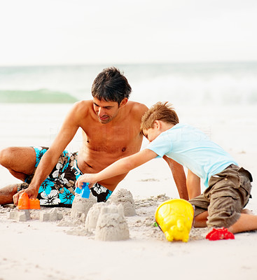 Father helping his son make sand castles at the beach