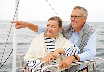 Mature couple on a sea voyage, man pointing away