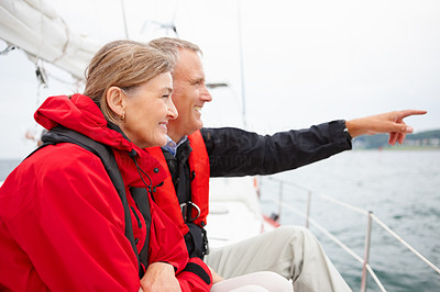 Senior couple on a sea voyage, pointing away