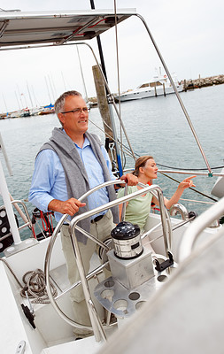 Retired man steering a boat with his wife at the back