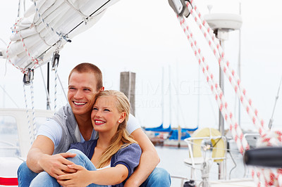 Young couple sitting together on a sailboat, looking away
