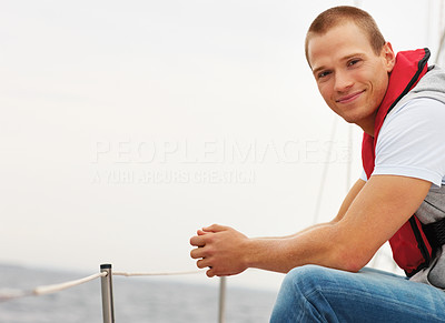 Smart guy wearing a life jacket sitting isolated in a sailboat at sea