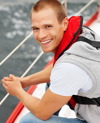 Smart young guy wearing a life jacket in a sail boat at sea