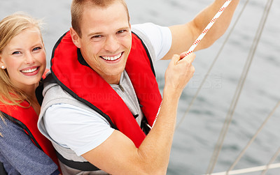 Happy young couple holding a boat line while on a adventurous sea voyage