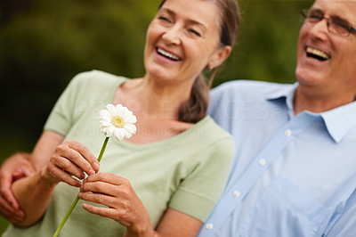 Happy mature woman holding a flower standing by husband