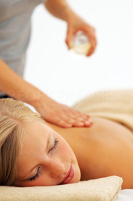 Young woman enjoying a back massage at the spa, masseuse using oil to massage
