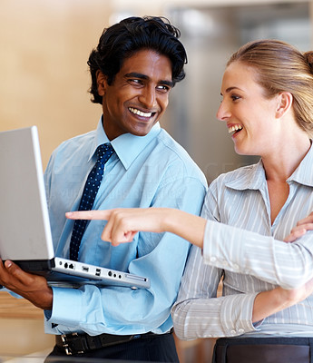 Happy business woman pointing at the laptop held by a colleague
