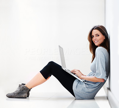 Young lady sitting on floor working on a laptop smiling