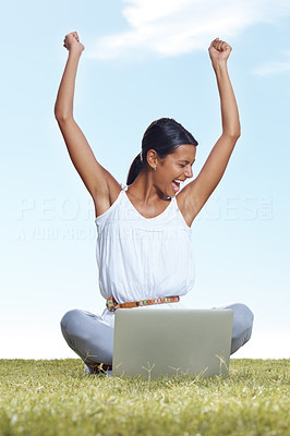 Screaming young lady with a laptop sitting on grass
