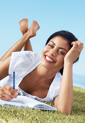 Happy woman writing notes while lying on grass