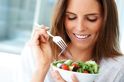 Happy young lady eating vegetable salad