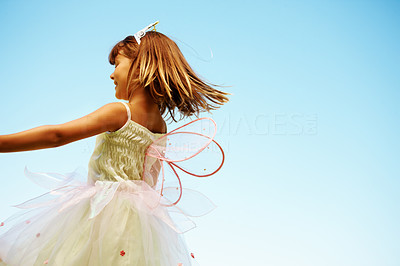 Young girl with fairy wings playing against blue sky