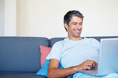 Happy man surfing his laptop at home