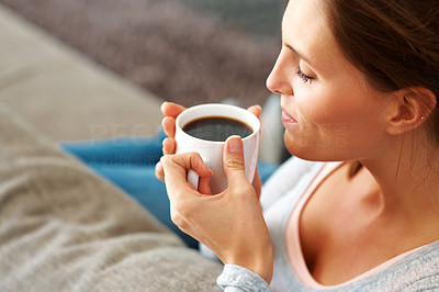 Relaxed young lady enjoying a cup of black coffee at home