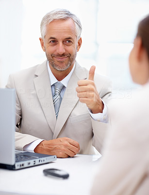 Mature business man showing thumbs up sign to his coworker