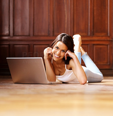 Relaxed young lady lying on floor with laptop