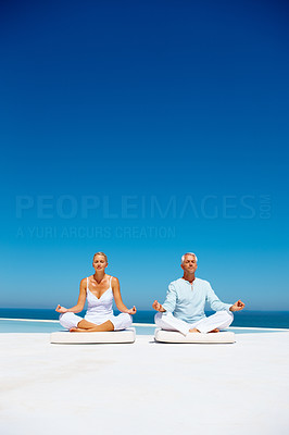 Relaxed mature couple meditating on the beach