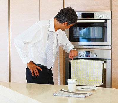 Business male standing by the oven in the kitchen