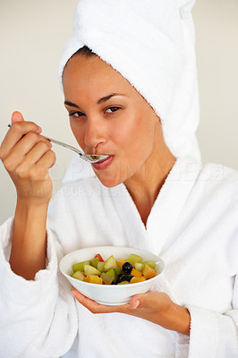Cute female in bath robe eating fruits
